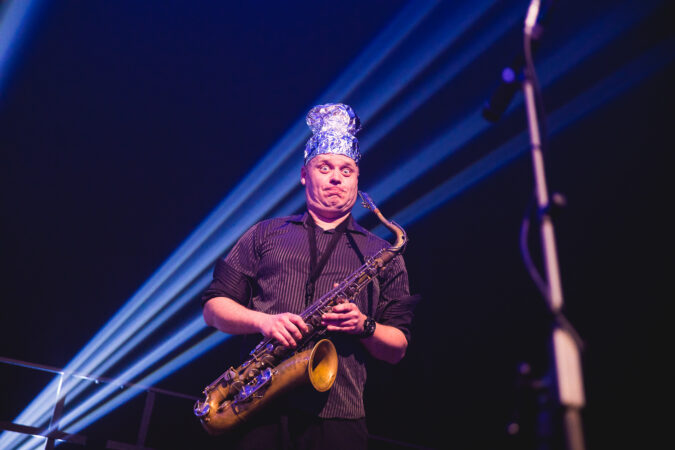 Saxofonista hraje na pódiu v modrém světle