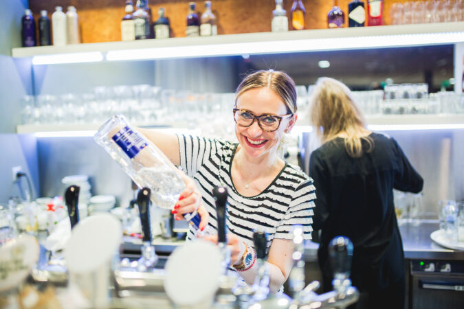 Barmanka připravuje míchaný nápoj za barem