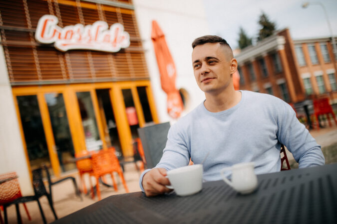 Muž s šálkem kávy sedí na terase kavárny